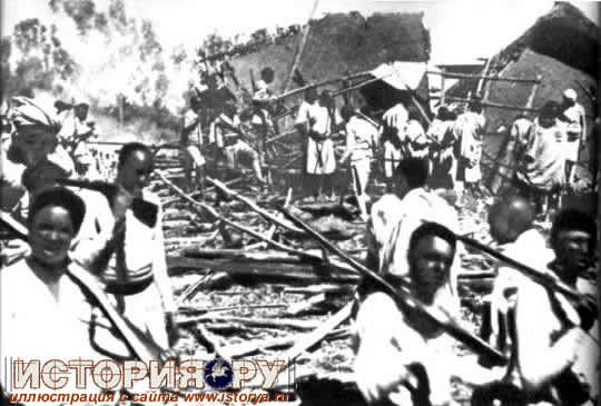 Эфиопский военный отряд проходит через селение, разрушенное итальянской авиацией, 1935г